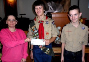 Jennifer McKibben, left, senior chemist for Ohio Valley Electric Corp. of Cheshire, hands a check to Life Scout Daniel Dunfee, of Meigs County Troop 299 on Dec. 12, 2014, while one of its new scouts, Blake Pitchford, looks on.  OVEC contributed $200 to the troop to assist with ongoing activities, and for scouts that may need help raising funds for camp.  Troop 299, led by veteran Scoutmaster Greg McCall, recently celebrated its 20th anniversary and 22nd scout to achieve Boy Scouting’s highest rank of Eagle.   