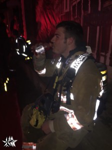 A fireman takes a moment to rest and drink water. Several people brought cases of bottled water to the scene for the firefighters. Photo by Carrie Gloeckner.